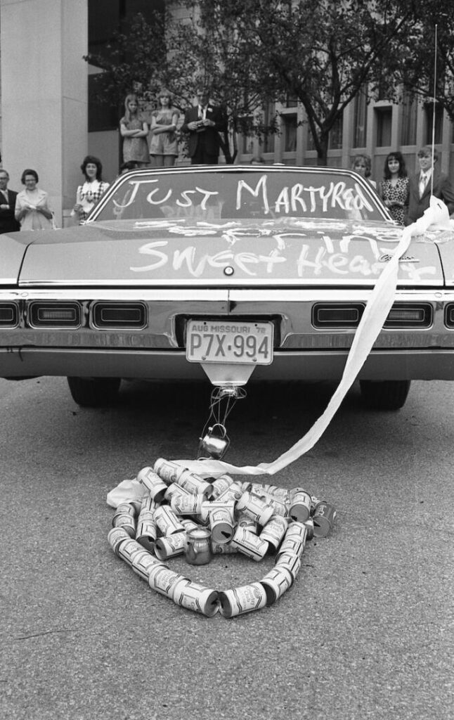 a car parked on the side of the road with a bunch of bottles tied to